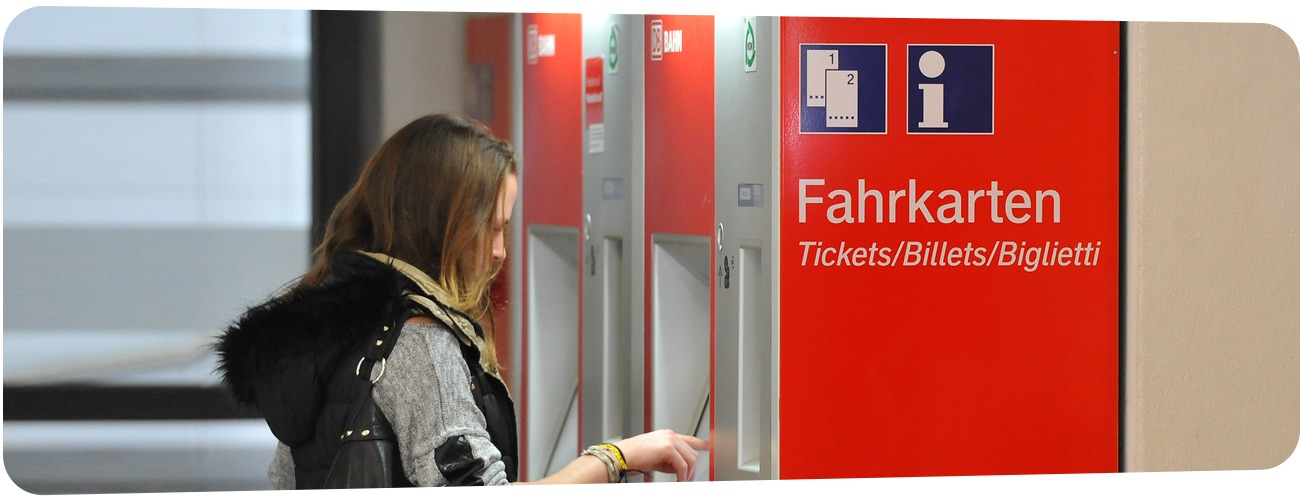 Abbildung einer Frau, die sich am Fahr­kar­ten­au­to­maten ein Ticket kauft